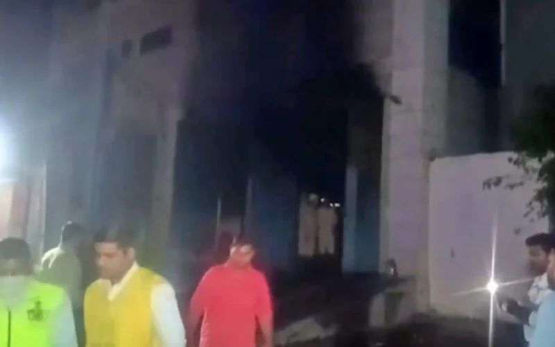 Smoke and emergency vehicles outside a shoe factory in Mangolpuri Industrial Area, Delhi, after a fire