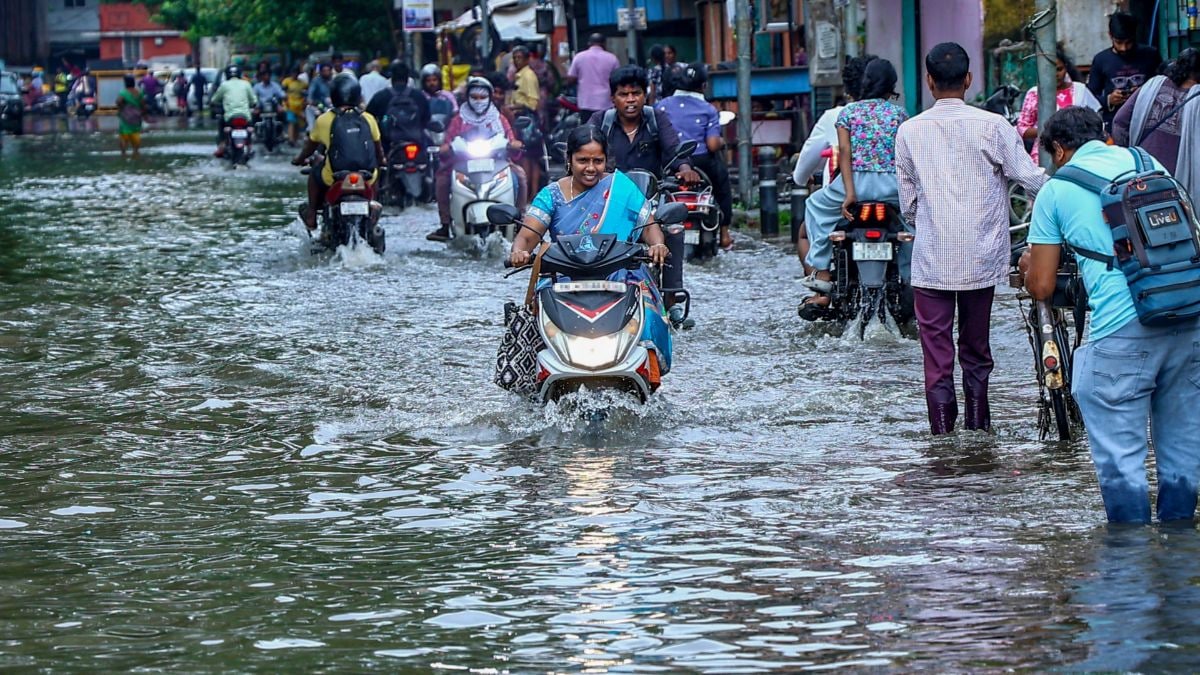 Commuters wade through a waterlogged street after heavy rain in Chennai