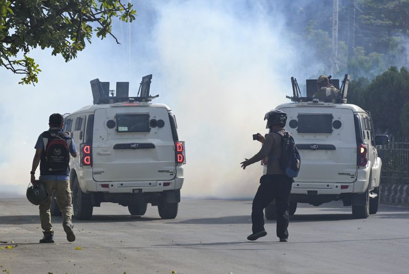 Police fire tear gas shells to disperse protesters on a street in Imphal, Manipur