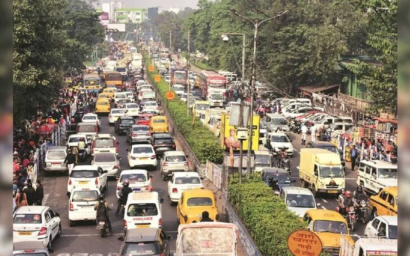 Cars and two-wheelers in traffic on a busy Indian city road