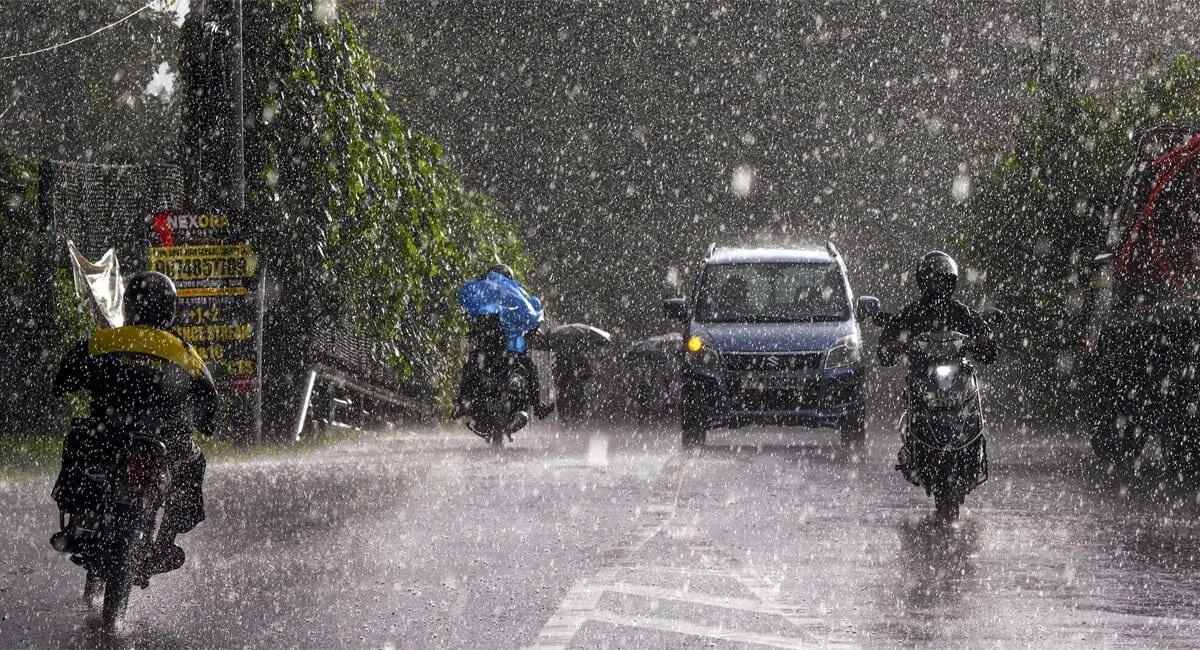 Commuters move along a street during rainfall in Kerala