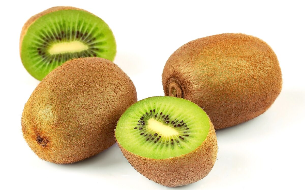 Whole and halved kiwi fruit showing green flesh and black seeds