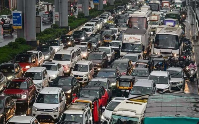 Vehicles moving through traffic on a Mumbai road in hazy air
