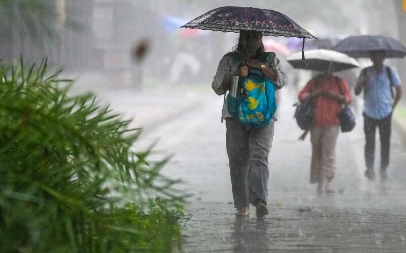 Commuters walk on a road in heavy rain in New Delhi