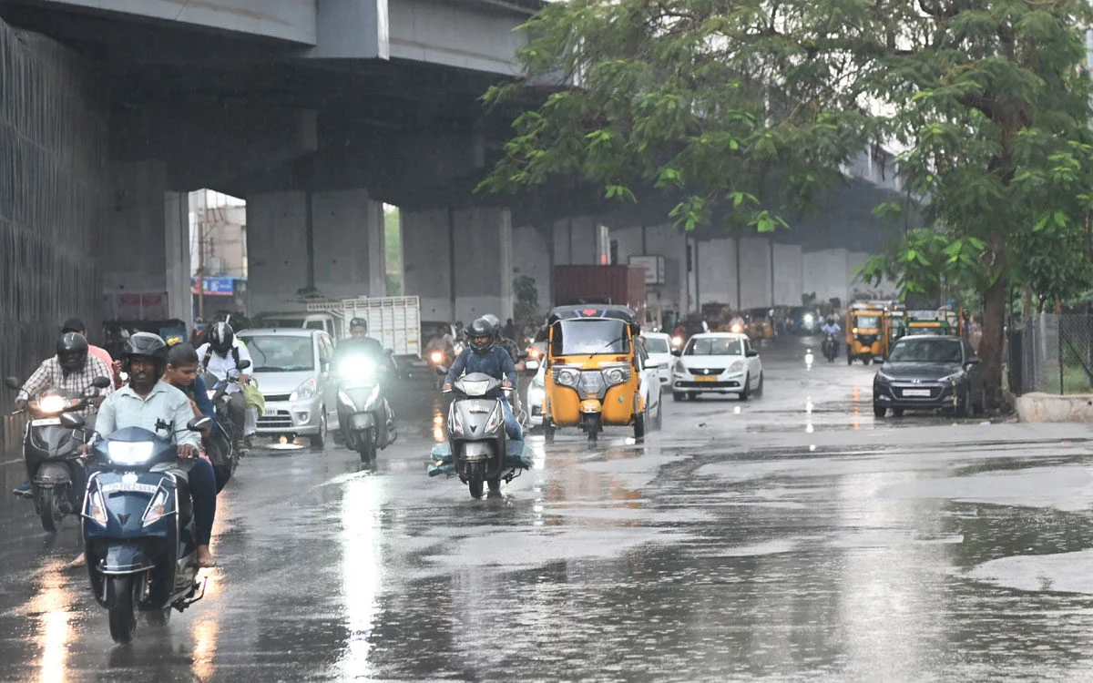 Commuters and vehicles on a rain-soaked road in Telangana