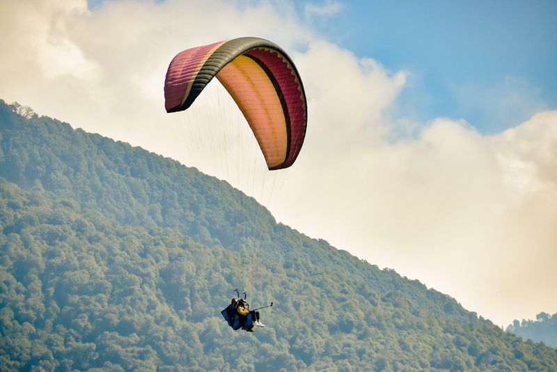 A paraglider flying over the hills of Uttarakhand during tandem flight training